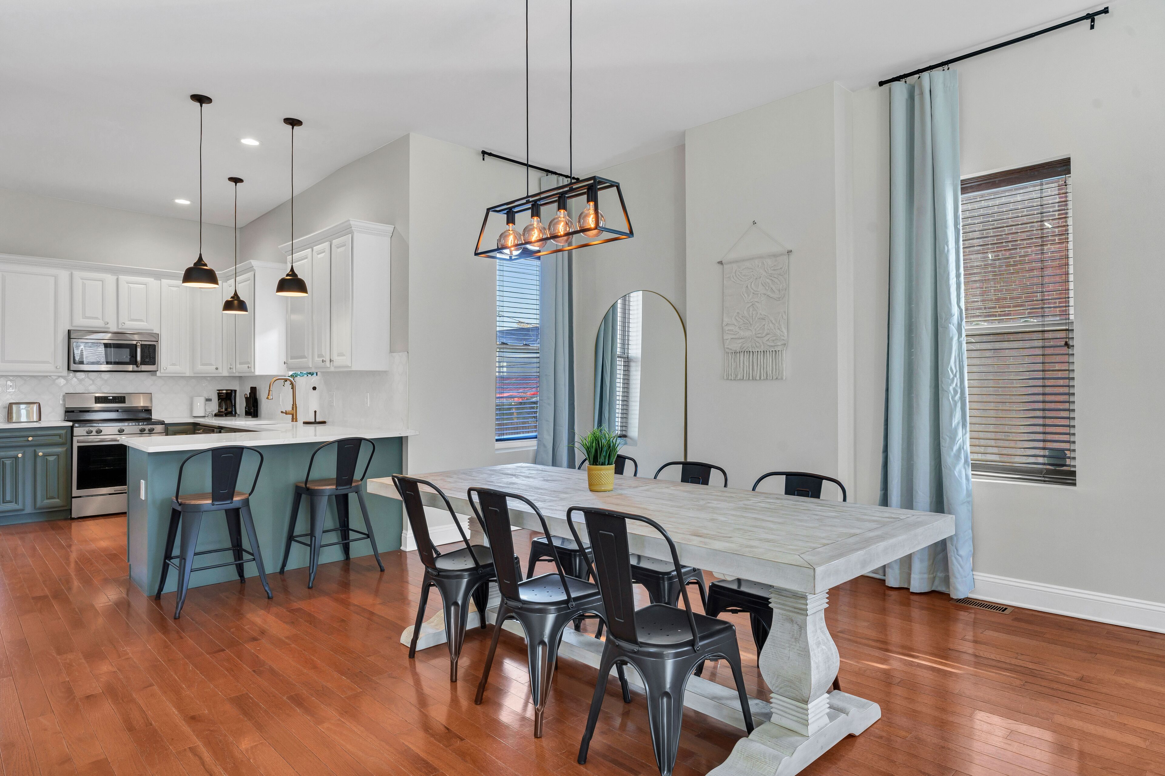 A modern kitchen with white cabinets, a central island with bar stools, and pendant lighting.