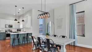 Een moderne keuken met witte kasten, een centraal eiland met barkrukken en hanglampen.