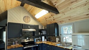 A modern kitchen with dark cabinets, a stainless steel stove, and a white refrigerator. - Cozy CABIN on a PRIVATE LAKE in Cabot, AR (Cabot)