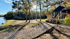 A cabin with a deck, surrounded by trees and a lake. - Cozy CABIN on a PRIVATE LAKE in Cabot, AR (Cabot)