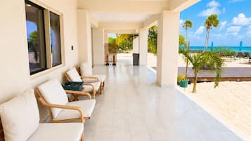 A covered outdoor seating area with chairs and a view of the beach.