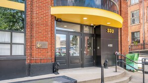 A building entrance with a black door, a yellow awning, and the number 333. - The 333 Suites 301 - Suite for 6 (Cincinnati)