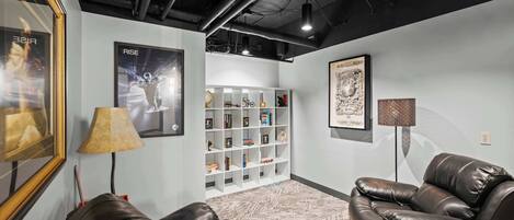 Un espace de détente moderne avec des canapés en cuir, une bibliothèque et des œuvres d’art encadrées accrochées aux murs.