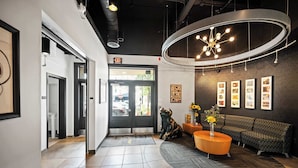 A modern lobby with a reception desk, a sofa, a coffee table, and framed pictures on the wall. - The 333 Suites 301 - Suite for 6 (Cincinnati)