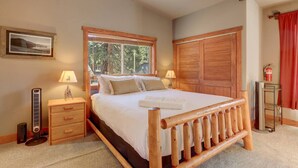 A bedroom with a wooden bed, two bedside tables with lamps, a window, a wardrobe, and a framed picture on the wall. - Knotty by Nature - Hot Tub, Pets & Fun - Oh my! (South Lake Tahoe)