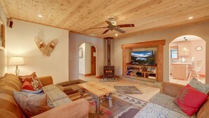 A cozy living room with a fireplace, wooden furniture, and a TV mounted on the wall. - Knotty by Nature - Hot Tub, Pets & Fun - Oh my! (South Lake Tahoe)
