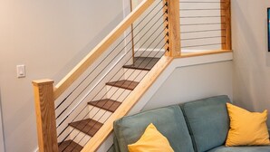 Una escalera con barandillas de madera y un sofá azul acolchado con cojines amarillos.