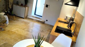 A modern kitchen with a built-in oven, a sink, and a dining area with a table and chairs. - Casa Liã Guest House (Septfonds)