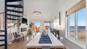 A spacious dining area with a long table, chairs, and a spiral staircase. - Oceanfront Penthouse with Pool & Stunning Beach Views in Murrells Inlet (Murrells Inlet)