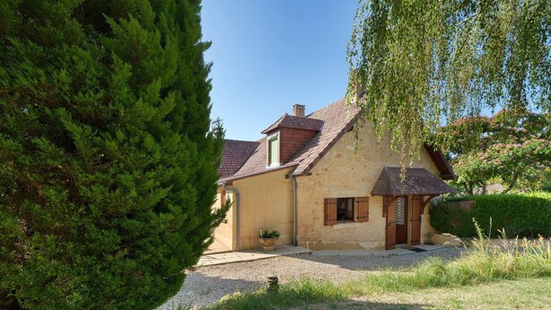 A house with a sloped roof, a small porch, and a gravel driveway. - Holiday Home 'Écrin de Verdure' with Private Terrace, Shared Garden and Wi-Fi (Sarlat-la-Canéda)