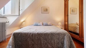 Une chambre à coucher avec un lit, un grand miroir, un radiateur et une fenêtre.