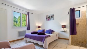Ein Schlafzimmer mit einem Bett, zwei Nachttischen, einem Fenster, einer Heizung und einer Dusche.