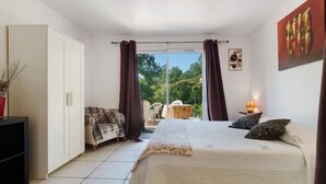 A bedroom with a bed, curtains, a wardrobe, a TV stand, and a view of the outdoors. - Bed and Breakfast 'Chambre Chocolat' with Shared Pool, Shared Terrace and Wi-Fi (Saint-André d'Allas)