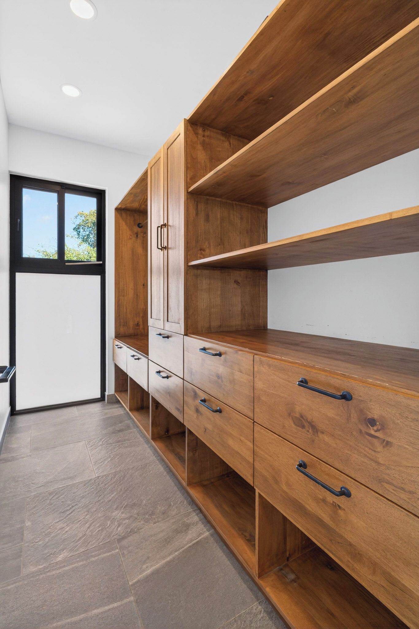 Ein modernes Interieur mit einem Holzkabinett, einem Fenster und einem Fliesenboden.