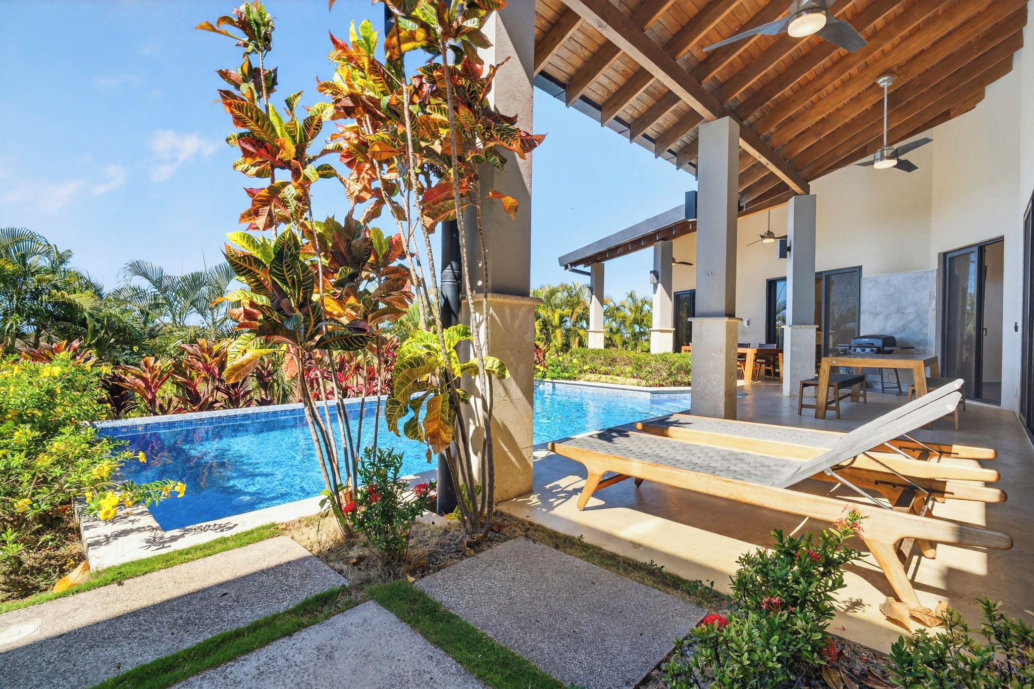 A modern outdoor pool area with lounge chairs and a covered patio.
