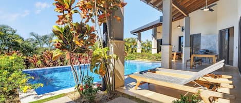 A modern outdoor pool area with lounge chairs and a covered patio.