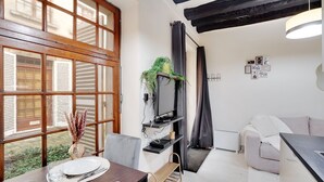 Una sala de estar moderna con comedor, ventanas grandes, televisor de pantalla plana y una zona de estar acogedora.
