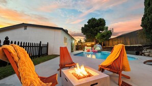A backyard with a swimming pool, two lounge chairs, and a fire pit. - Hot Tub/Pool/Fire Pit/10 Mins to Beach (San Diego)