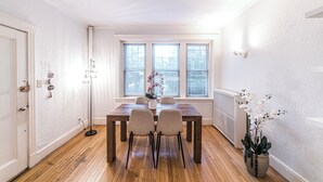 Ein Essbereich mit einem Holztisch, zwei Stühlen, einer Blumenvase und einem Fenster mit Jalousien.