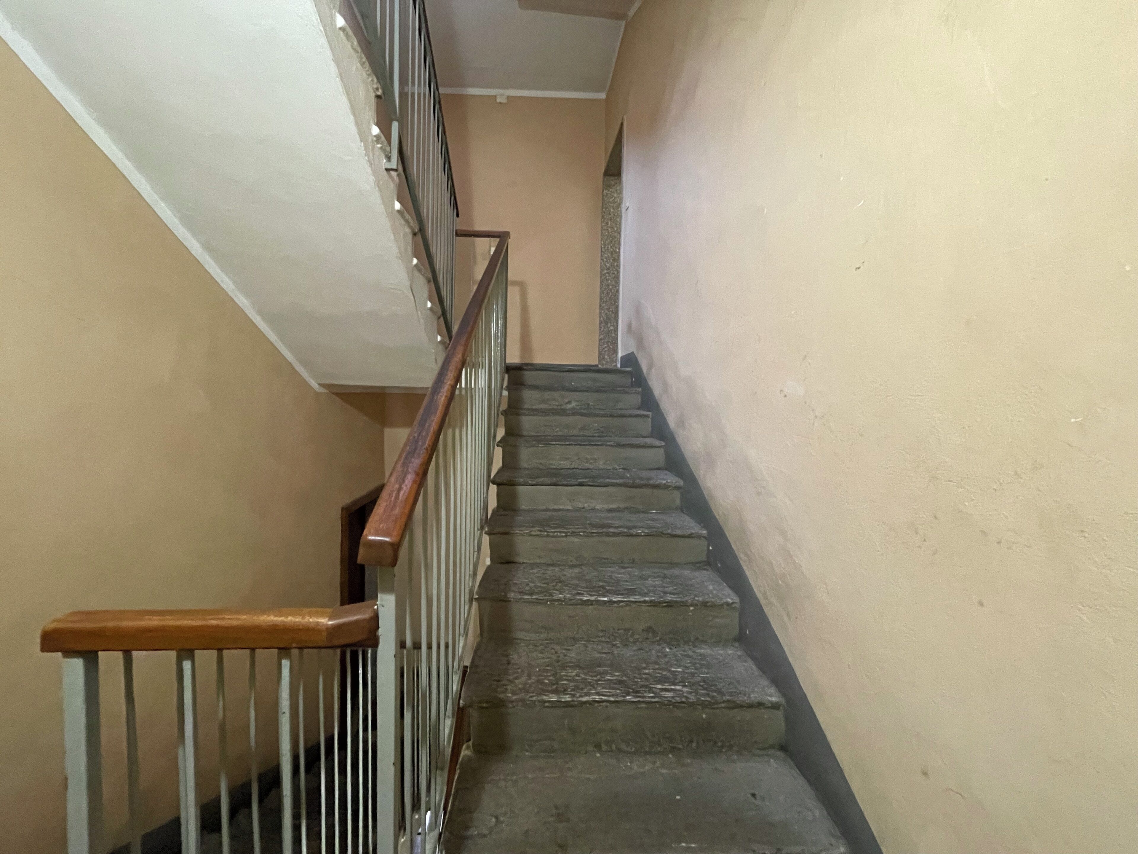 Una scala con ringhiera in legno e balaustre in metallo, che conduce a un piano superiore.