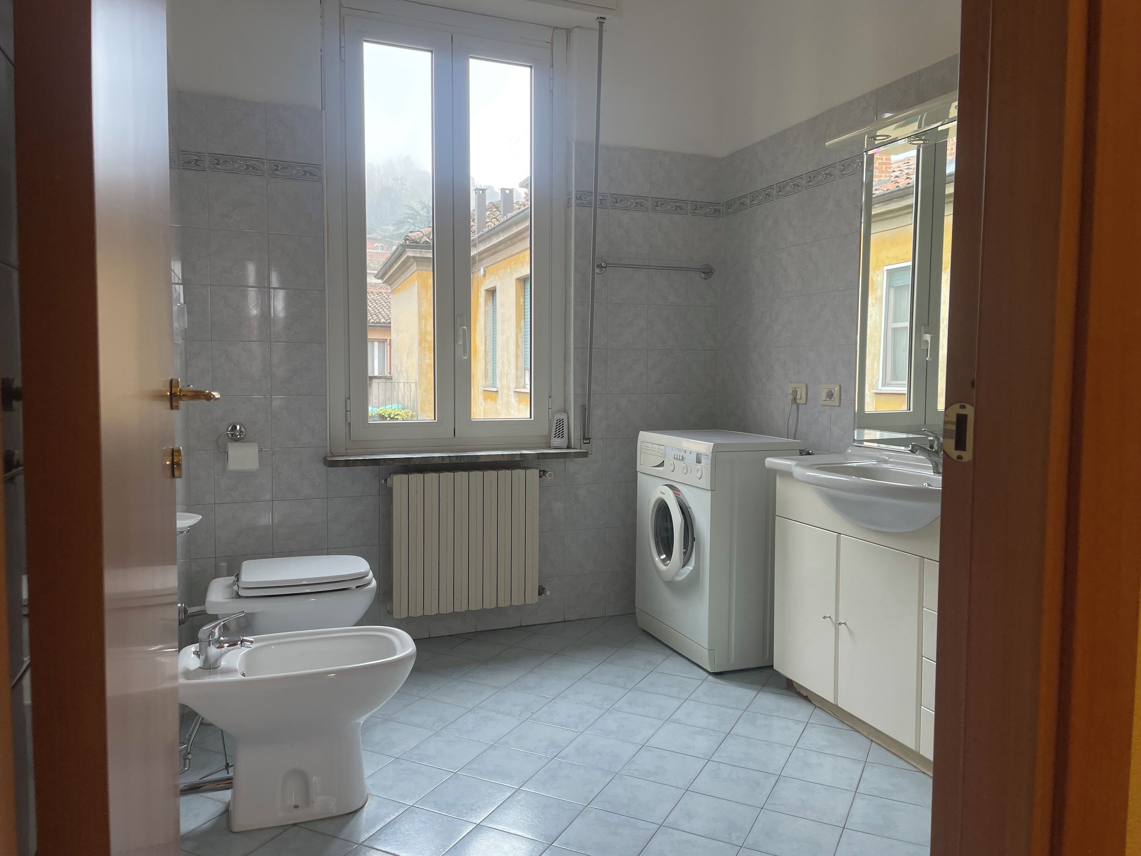 Une salle de bain équipée de toilettes, d’un bidet, d’un lave-linge et d’un lavabo.