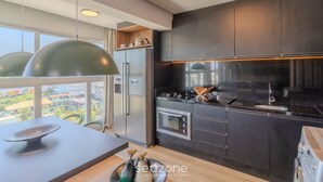 A modern kitchen with dark cabinetry, stainless steel appliances, and pendant lighting. - Modern and Complete Apartments in Itajai - RVC (Itajai)