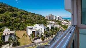 A residential area with modern buildings, a clear view of the sea, and a lush green hillside. - Modern and Complete Apartments in Itajai - RVC (Itajai)