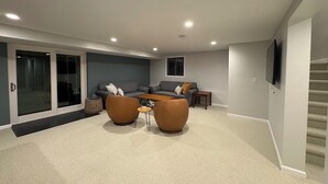 Un salon moderne comprenant un canapé, deux fauteuils, une table basse et un téléviseur.