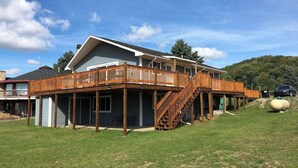 Une maison à deux étages dotée d’une terrasse en bois et d’un escalier menant à l’étage supérieur.