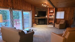 L’intérieur chaleureux d’un chalet avec une cheminée, des murs en bois et un coin salon confortable.