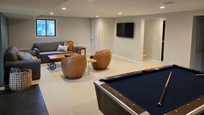 Un salon moderne avec une table de billard, un canapé et un téléviseur.
