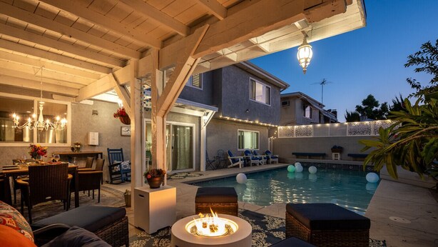 Un patio exterior con piscina, asientos y una chimenea.
