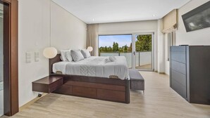 A modern bedroom with a large bed, a desk, and a balcony with a view. - Villa Caripira by Villa Plus (Albufeira)