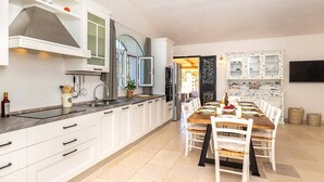 Eine moderne Küche mit weißen Schränken, einer zentralen Kochinsel und einem Essbereich mit Holztisch und Stühlen.