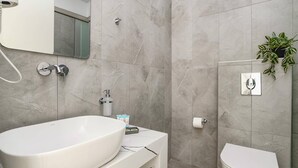 Een moderne badkamer met een vrijstaand bad, een toilet en een wastafel.