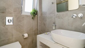 Ein modernes Badezimmer mit einem großen, weißen Waschbecken, einem Spiegel und einer Dusche.