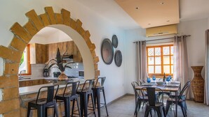 Eine moderne Küche mit Ziegelbogen, einem Essbereich mit Tisch für vier Personen und einem großen Fenster mit Vorhängen.