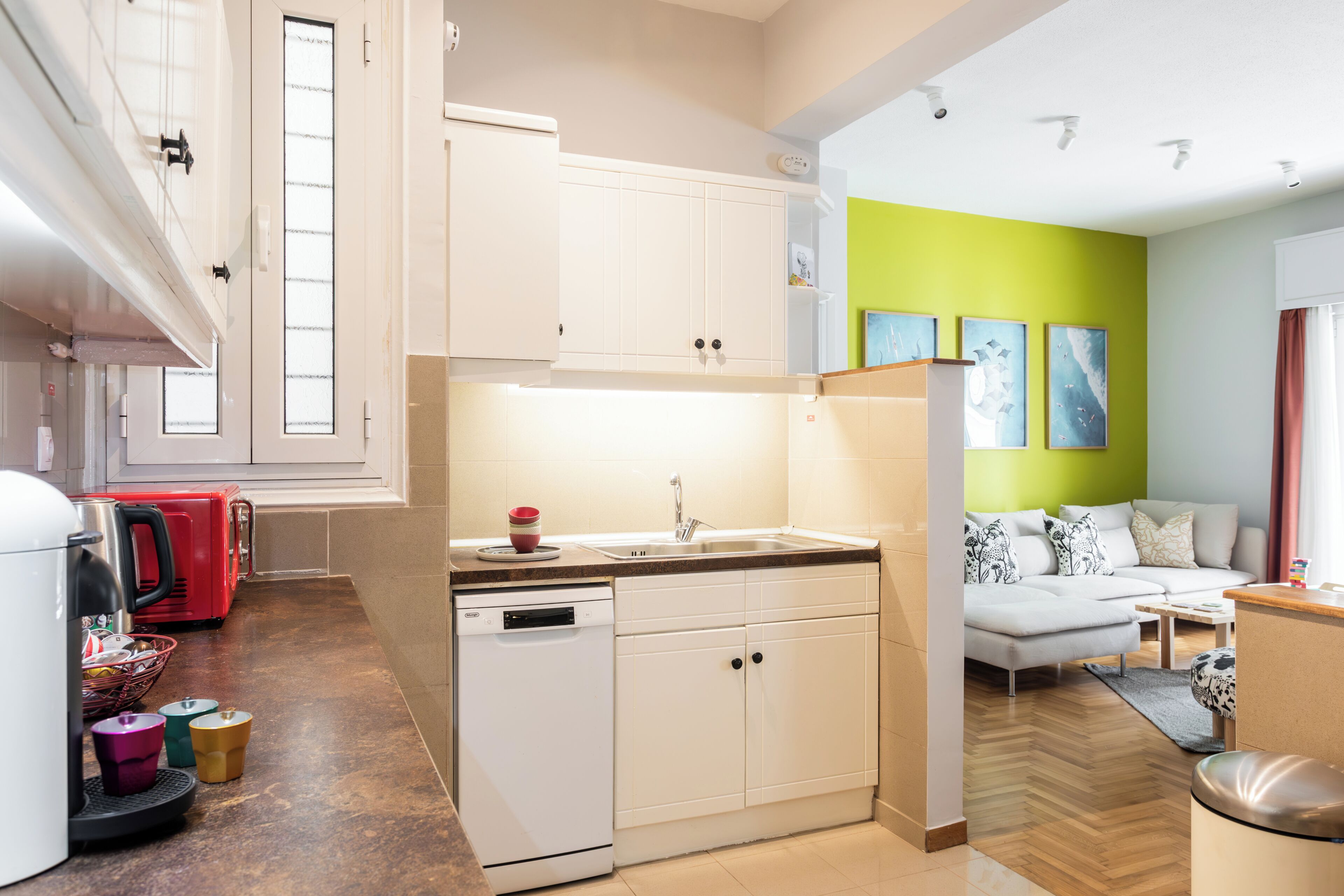 A modern kitchen with white cabinets, a dishwasher, and a red appliance.