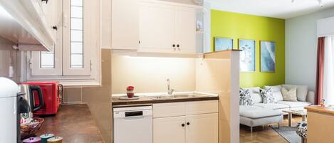 A modern kitchen with white cabinets, a dishwasher, and a red appliance.
