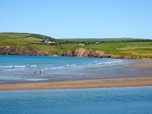 Eine Küstenlandschaft mit Strand, Klippen und grünen Hügeln.