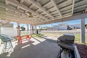 Un espacio al aire libre techado con una parrilla, una mesa de picnic y sillas.