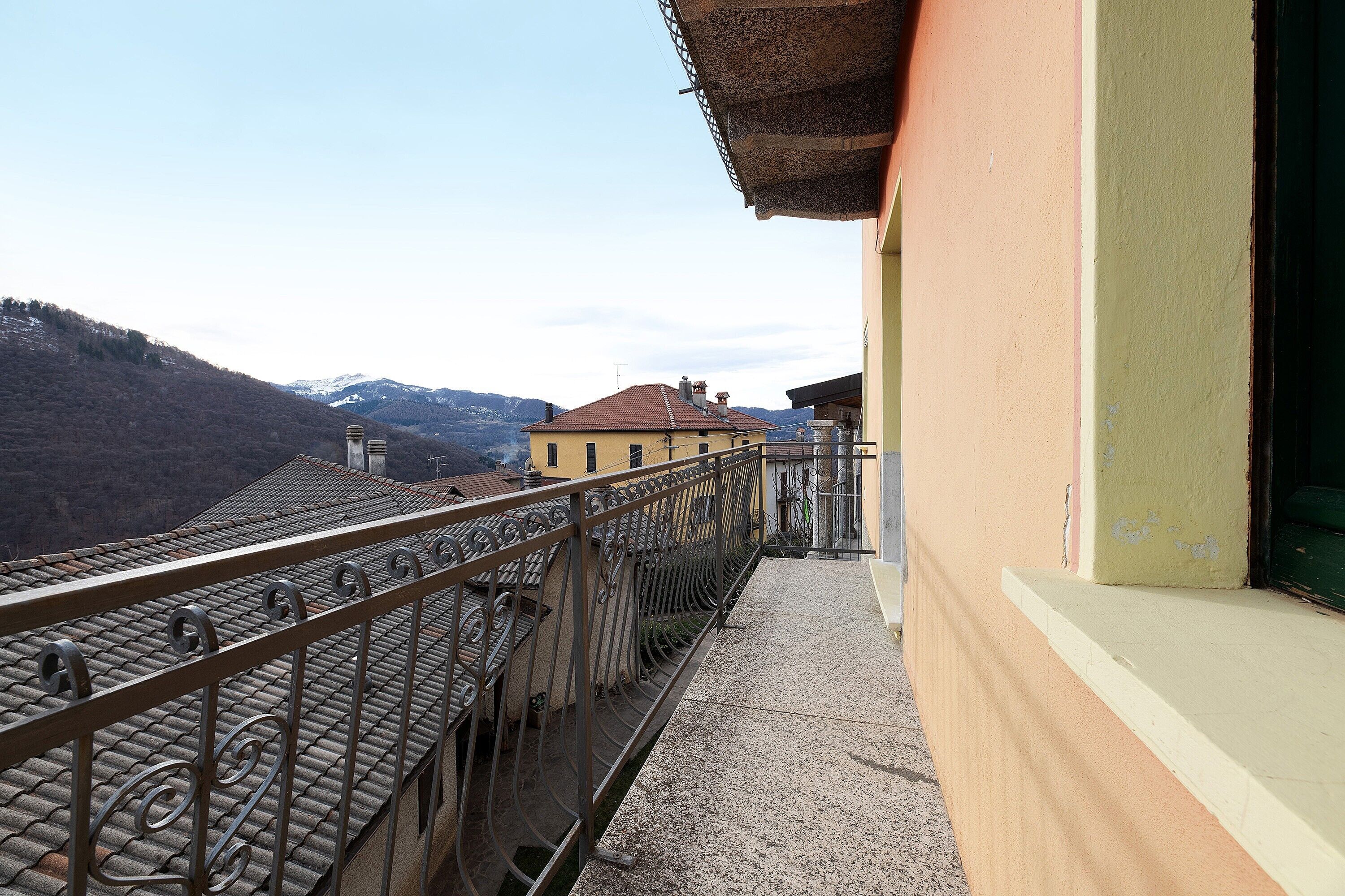 Un balcone con ringhiera in metallo che si affaccia su un paesaggio montuoso.