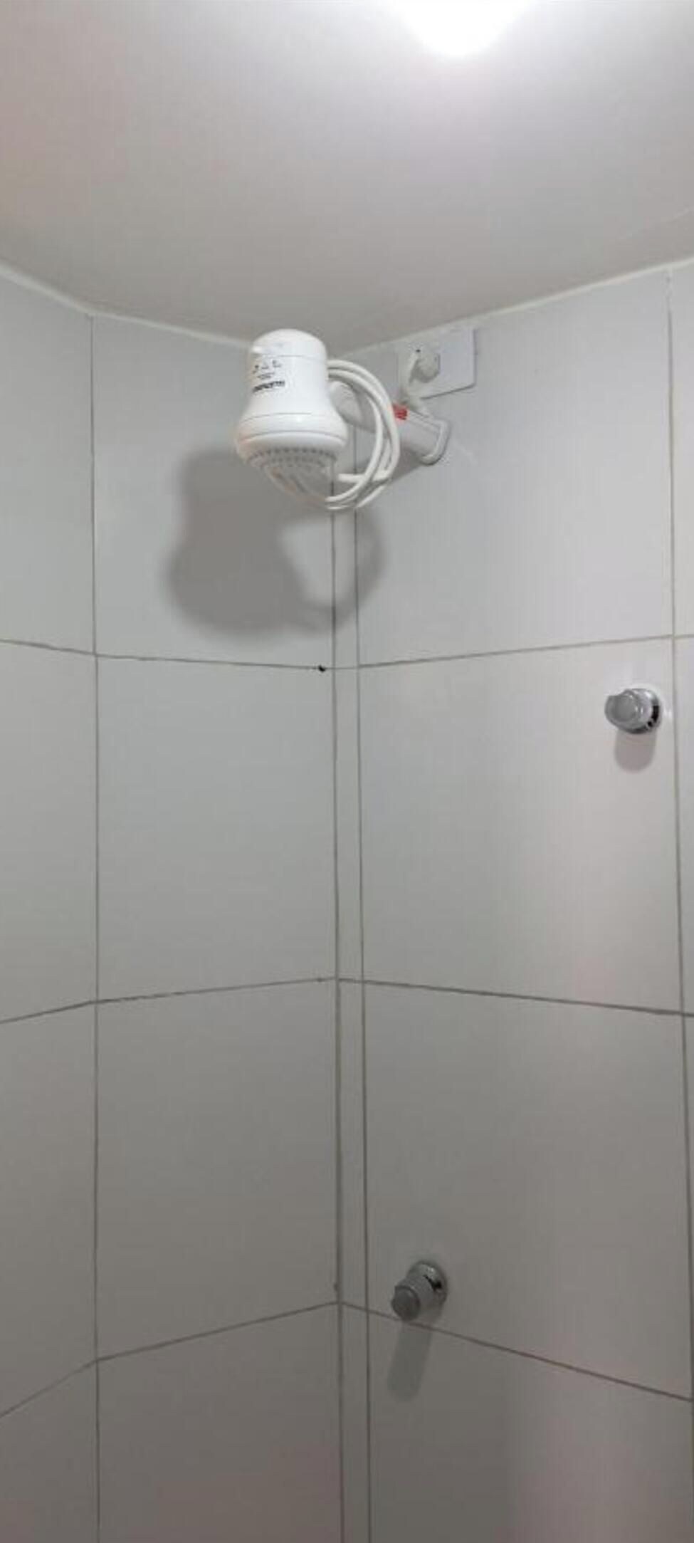 A tiled shower enclosure with a handheld showerhead mounted on the wall.