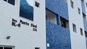 A multi-story building with a white facade and blue accents. It has a sign indicating "Res. Monte Sinaí BL-A 235". - Apartamento novo em João Pessoa  (João Pessoa)
