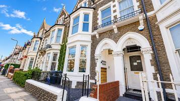 A row of Victorian-style terraced houses with bay windows, a brick facade, and a white front door.