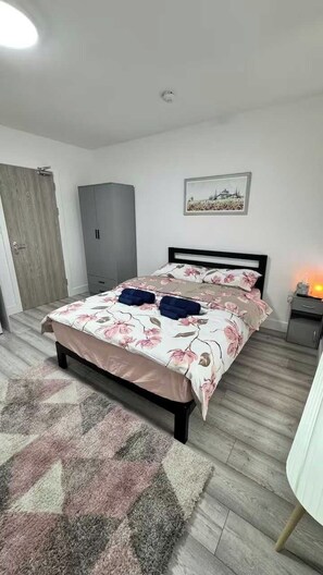 Ein Schlafzimmer mit Bett, Kleiderschrank, Nachttisch und einem Bild an der Wand.