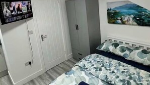A bedroom with a bed, a wardrobe, a television mounted on the wall, and a painting. - Modern Studio with Fast Wifi! (Cardiff)