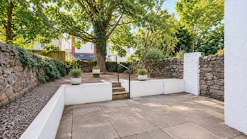 A patio area with stone walls, potted plants, and a staircase leading to an upper level.