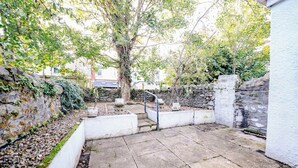 A stone-paved courtyard with a tree, stone walls, and a white building. - Modern Studio with Fast Wifi! (Cardiff)