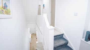 A narrow staircase with white walls and a blue carpet.